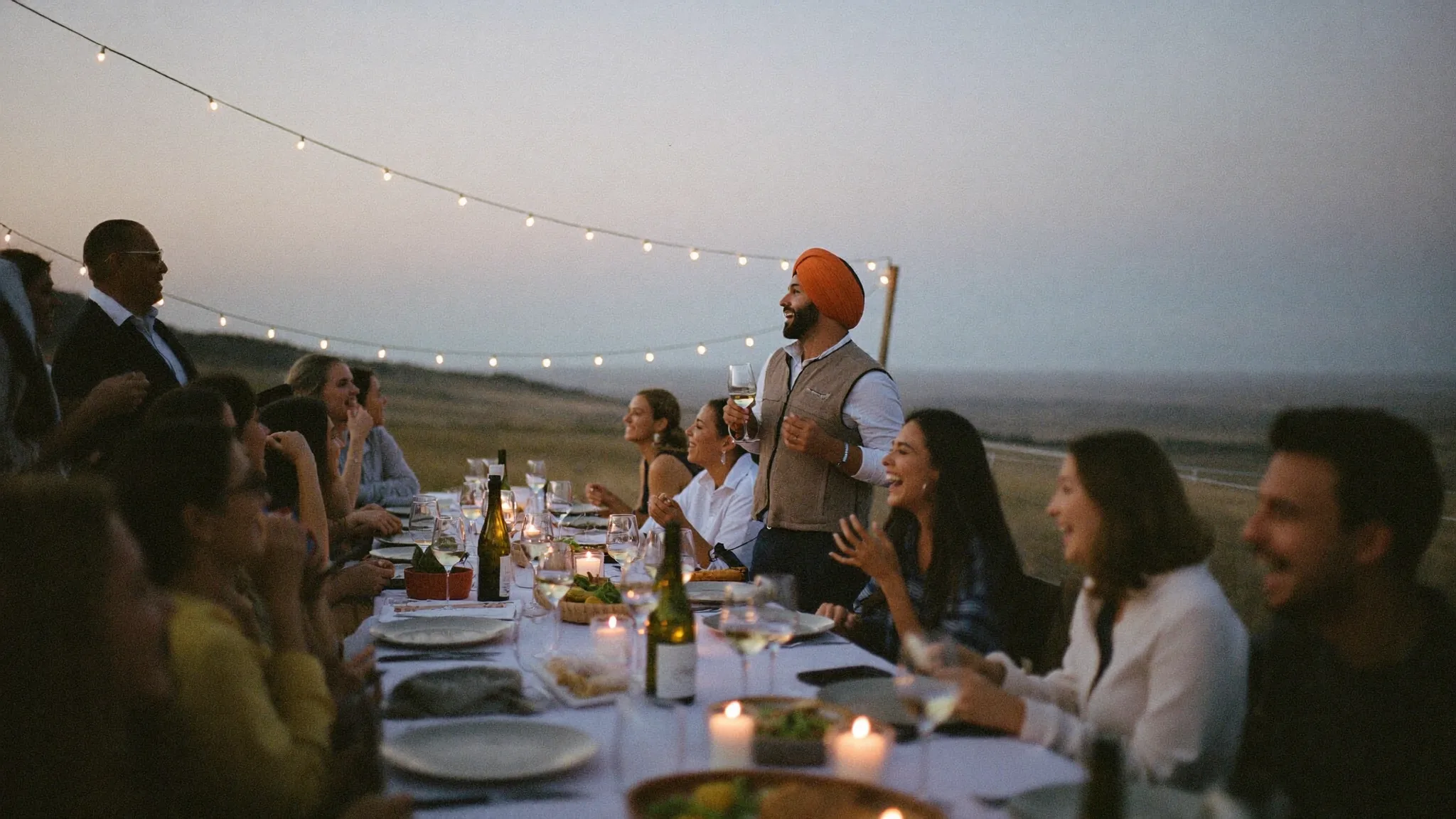 Long dinner table outdoors at dusk, laptops closed
